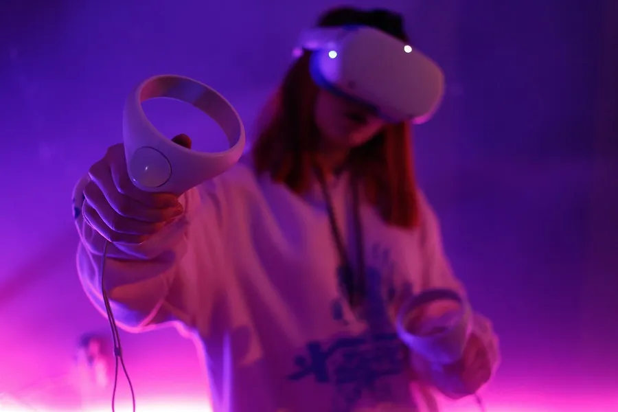 A girl wearing VR headset and holding controllers to play VR badminton games