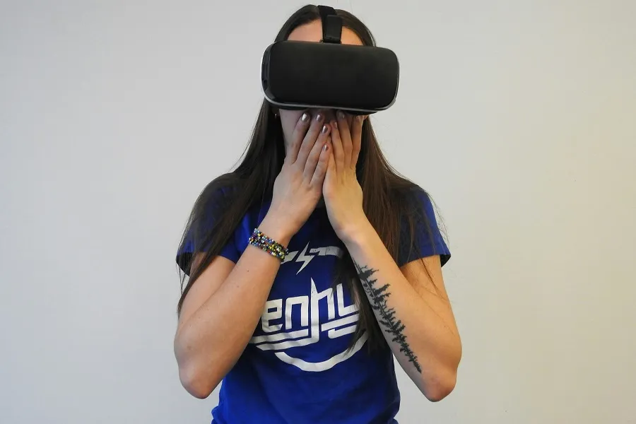 A lady wearing Meta Quest 4 VR headset covering mouth with hands, wearing a blue shirt